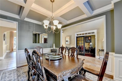 Dining room with a decorative wall, wainscoting, arched walkways, crown molding, and beamed ceiling