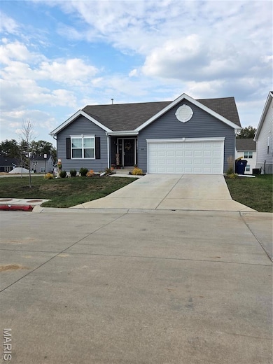 Ranch-style house featuring a front lawn, concrete driveway, an attached garage, and roof with shingles