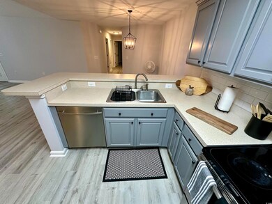 Kitchen with a sink, dishwasher, a peninsula, gray cabinets, and light countertops