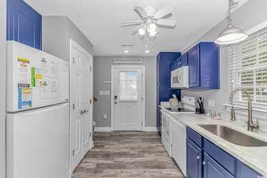 Kitchen featuring blue cabinets, sink, white appli