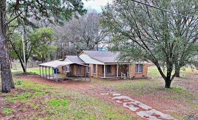Ranch-style home with brick siding, a carport, covered porch, a shingled roof, and crawl space