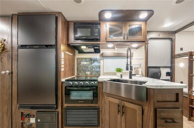 Kitchen featuring black appliances, extractor fan, a sink, brown cabinets, and glass insert cabinets