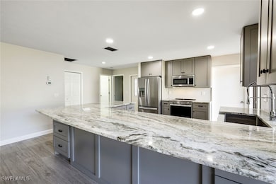 Kitchen offers light gray custom cabinetry with bu
