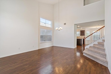 Unfurnished living room featuring a chandelier, d