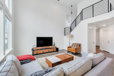 Living area featuring a towering ceiling, stairs, and wood finished floors