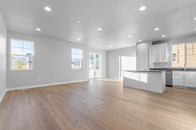 Kitchen with white cabinetry, dark countertops, recessed lighting, open floor plan, and a center island