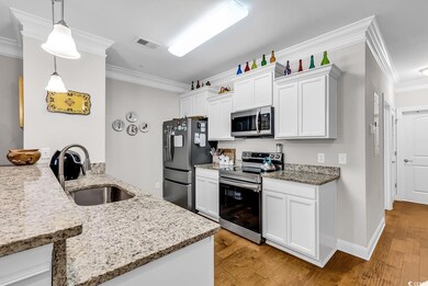 Kitchen with stainless steel appliances, a sink, crown molding, light wood-style floors, and light stone counters