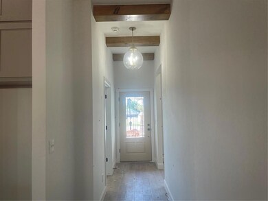 Hallway featuring beam ceiling and light hardwood 