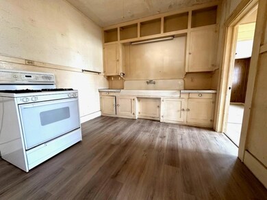 Kitchen with white gas range oven, light brown cab