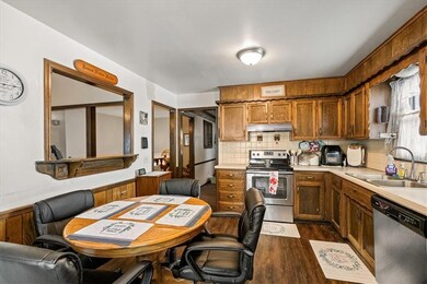 Kitchen featuring stainless steel appliances, decorative backsplash, light countertops, dark wood-style floors, and brown cabinetry