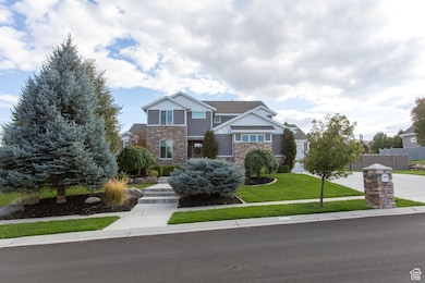 View of front facade featuring stone siding, a front yard, board and batten siding, and concrete driveway