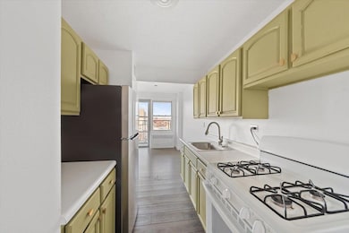 Kitchen with light countertops, radiator heating unit, gas range gas stove, and a sink