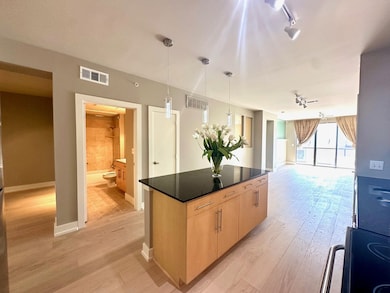 Kitchen with light brown cabinetry, visible vents, light wood finished floors, and dark countertops