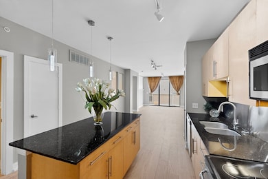 Kitchen with rail lighting, stainless steel microwave, black / electric stove, and light wood-style floors