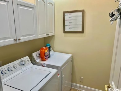 Washroom with washing machine and clothes dryer, cabinet space, and baseboards