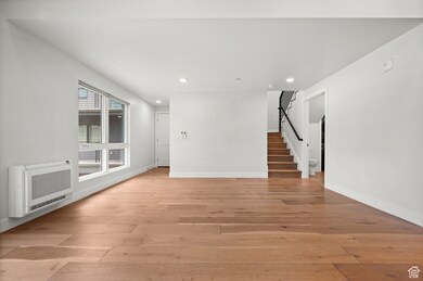 Unfurnished room featuring heating unit, stairway, recessed lighting, and light wood-type flooring