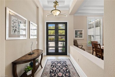 Tiled foyer featuring plenty of natural light, french doors, ornamental molding, and a raised ceiling