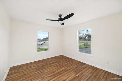 Empty room featuring ceiling fan, a wealth of natural light, and wood-type flooring