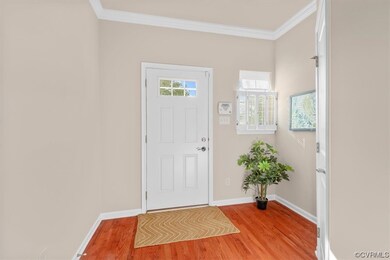 Hardwood floored entryway featuring crown molding