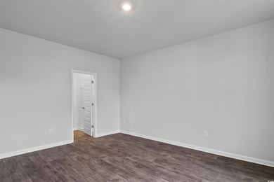 Empty room featuring baseboards and dark wood fini