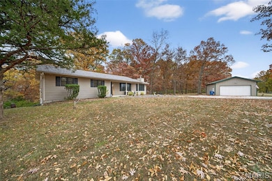 Ranch-style house featuring a garage, a front yard, a chimney, and an outbuilding