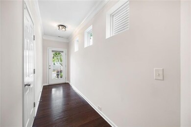 Corridor featuring dark wood-type flooring, crown molding, and baseboards