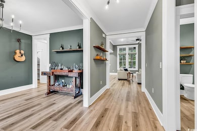 Hallway with crown molding, light wood-style flooring, baseboards, and a chandelier