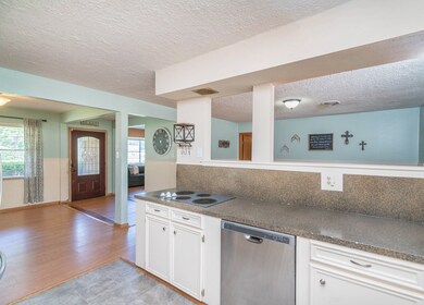 Continue beyond the foyer into the centrally located kitchen with stone look laminate countertops, white cabinetry, and a convenient pass-through bartop into the adjoining room that could be a breakfast room or an additional living space.