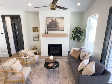 Living room featuring recessed lighting, wood finished floors, a glass covered fireplace, and a ceiling fan
