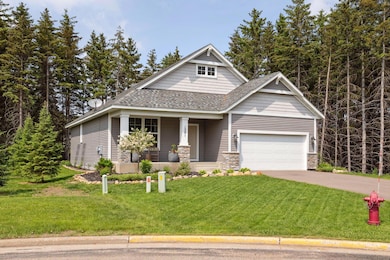 Front of home features front porch, beautifully landscaped lawn, and pine trees!