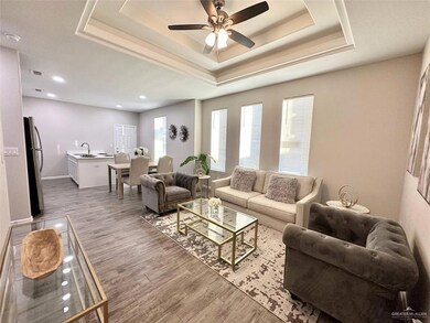 Living area with a tray ceiling, wood finished floors, a ceiling fan, and recessed lighting