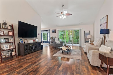 Living area featuring lofted ceiling, wood finished floors, and a ceiling fan