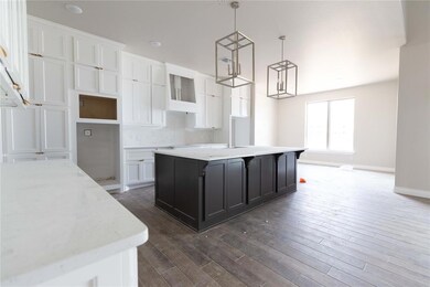 Kitchen with white cabinets, a kitchen island, dark wood-style flooring, baseboards, and a chandelier
