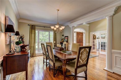 The formal dining room receives ample sunlight from a large window. Elegant wainscoting and crown molding details make this a lovely room for entertaining.