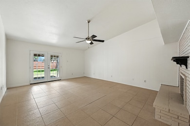 Unfurnished living room featuring vaulted ceiling, a ceiling fan, a brick fireplace, light tile patterned floors, and a textured ceiling