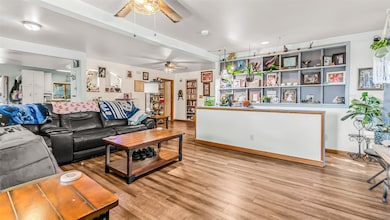 Living area featuring a ceiling fan, light wood fi