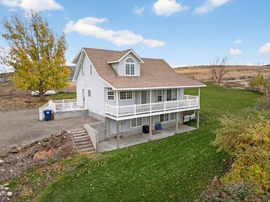 Back of property with a shingled roof, a yard, a patio area, and stairs