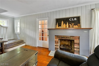 Living area with ornamental molding, wood-type flooring, a fireplace, stairway, and wooden walls