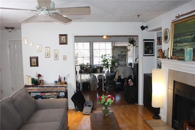 Living area featuring wood finished floors, a tiled fireplace, and a ceiling fan