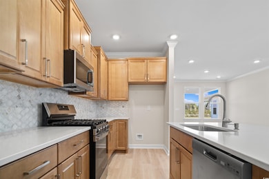 Kitchen featuring light countertops, a sink, crown molding, and appliances with stainless steel finishes