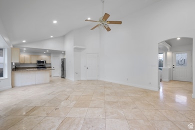 Unfurnished living room featuring high vaulted ceiling, recessed lighting, a ceiling fan, and arched walkways