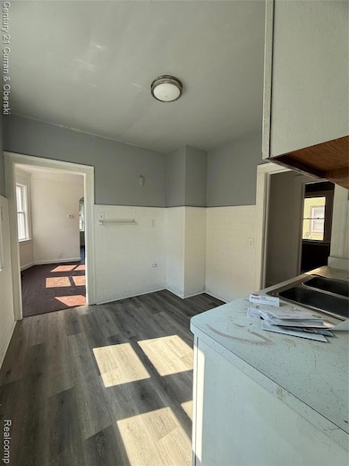 Kitchen featuring plenty of natural light, dark wood-style floors, wainscoting, and tile walls