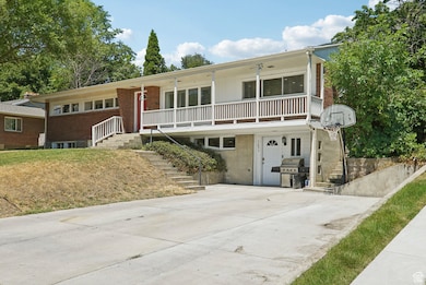 View of front of home featuring stairway, a porch, brick siding, and concrete driveway