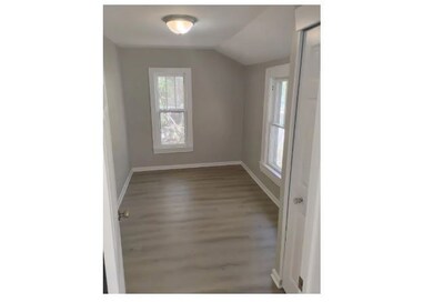 Spare room featuring wood finished floors and lofted ceiling