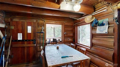 Cozy dining area with log cabin charm, large windows, and serene wooded views.