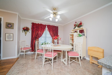 Dining area featuring a ceiling fan, crown molding, a textured ceiling, and baseboards