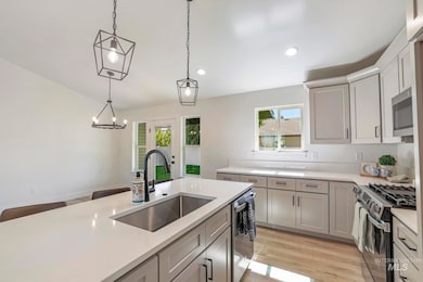 Kitchen featuring light wood-style flooring, appliances with stainless steel finishes, decorative light fixtures, gray cabinetry, and recessed lighting