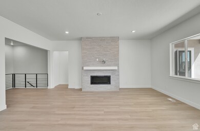 Unfurnished living room with light wood-type flooring, a stone fireplace, and recessed lighting