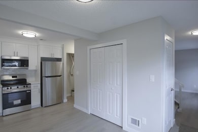 Kitchen featuring stainless steel appliances, white cabinets, light wood-type flooring, backsplash, and a textured ceiling