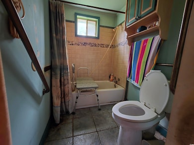Bathroom featuring shower / bath combo, ornamental molding, toilet, and tile patterned flooring
